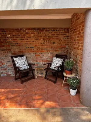 two chairs sitting on a patio with a brick wall at Olivestay at Olympus - Studio Apartment in Pretoria
