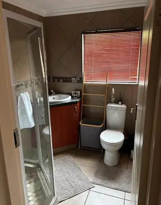 a bathroom with a toilet and a sink and a shower at Olivestay at Olympus - Studio Apartment in Pretoria