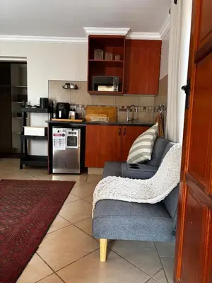 a living room with a couch and a kitchen at Olivestay at Olympus - Studio Apartment in Pretoria