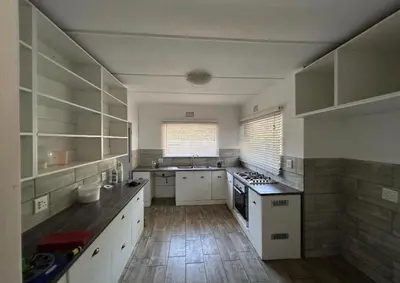 a large kitchen with white cabinets and a wooden floor at Madlabeezy in Kempton Park