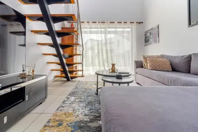 a living room with a couch and a spiral staircase at The View in Fourways