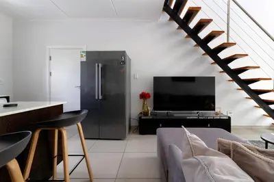 a living room with a couch and a tv and stairs at The View in Fourways