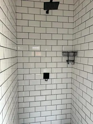 a white tiled bathroom with black and white fixtures at Crown on Milner in Pretoria