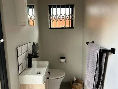 a bathroom with a toilet and a sink and a window at Crown on Milner in Pretoria