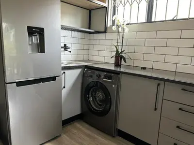a kitchen with a washing machine and a refrigerator at Crown on Milner in Pretoria
