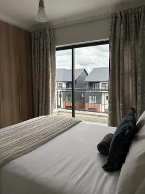a bed in a bedroom with a large window at The Dream Escape At The Blyde - One Bedroom Apartment in Pretoria