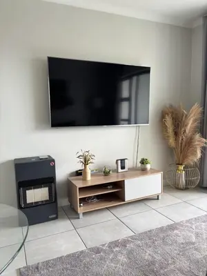 a living room with a flat screen tv on a wall at The Dream Escape At The Blyde - One Bedroom Apartment in Pretoria