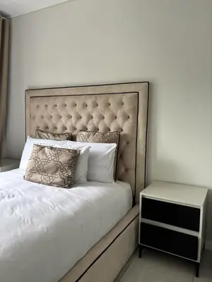 a white bed with a large headboard and a side table at The Dream Escape At The Blyde - Lagoon Facing 3 Bedroom Apartment in Pretoria