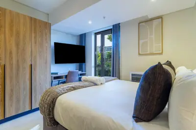 a bedroom with a large bed and a tv at #AlimamaSpaces Rob's Menlyn Maine in Pretoria