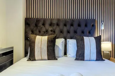 a bedroom with a bed with a black headboard and pillows at #AlimamaSpaces Rob's Menlyn Maine in Pretoria