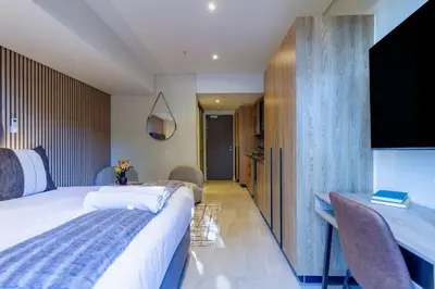 a bedroom with a large bed and a desk at #AlimamaSpaces Rob's Menlyn Maine in Pretoria