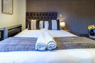a bedroom with a large bed with towels on it at #AlimamaSpaces Rob's Menlyn Maine in Pretoria