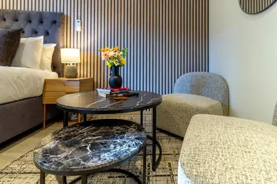 a hotel room with a table and two chairs and a bed at #AlimamaSpaces Rob's Menlyn Maine in Pretoria