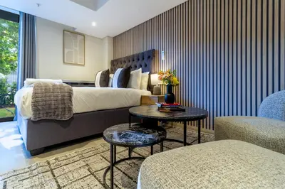 a bedroom with a bed and a table and two chairs at #AlimamaSpaces Manson's Menlyn Maine in Pretoria