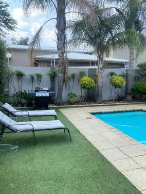a swimming pool with two lounge chairs next to a house at Andisa Cozy Stay in Kempton Park