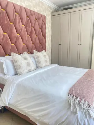 a bedroom with a large bed with a pink padded headboard at Andisa Cozy Stay in Kempton Park