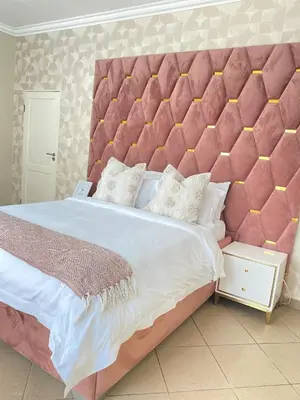 a large bed with a large pink padded headboard at Andisa Cozy Stay in Kempton Park