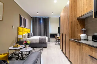 a hotel room with a bed and a kitchen at #AlimamaSpaces Chelsea's Menlyn Maine in Pretoria
