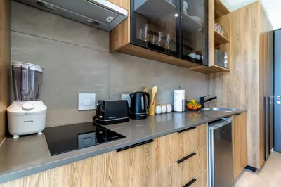 a kitchen with a black counter top and wooden cabinets at #AlimamaSpaces Chelsea's Menlyn Maine in Pretoria