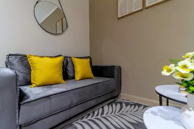 a grey couch with yellow pillows in a living room at #AlimamaSpaces Chelsea's Menlyn Maine in Pretoria