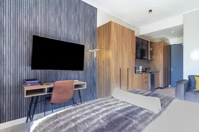 a bedroom with a bed and a tv on a wall at #AlimamaSpaces Chelsea's Menlyn Maine in Pretoria