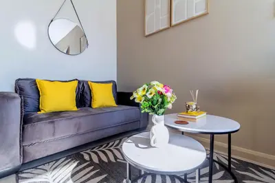 a living room with a couch and a table with flowers at #AlimamaSpaces Chelsea's Menlyn Maine in Pretoria