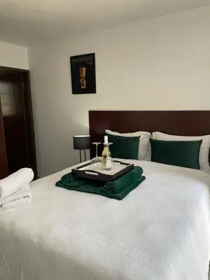 a bed with a tray with a bottle of perfume on it at Green View Guest House Middelburg in Middelburg