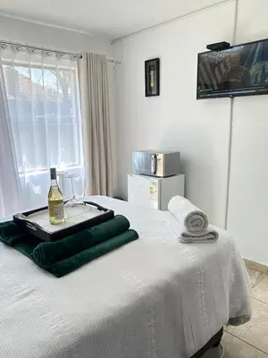 a white bed with a bottle of wine on it at Green View Guest House Middelburg in Middelburg