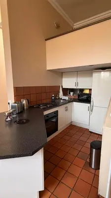 a kitchen with white cabinets and a black counter top at Contractor Stay Units in Middelburg