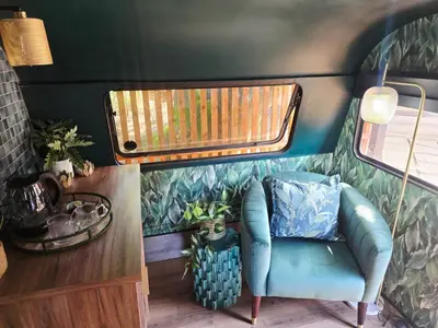 a room with a blue chair and a window at Tin Town Glamping in Haenertsburg