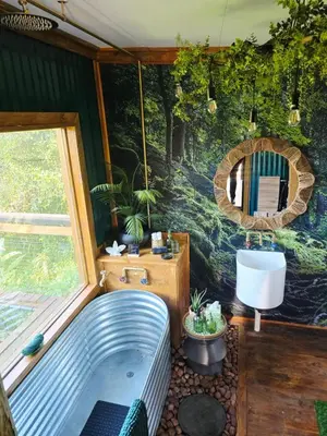 a bathroom with a tub in front of a wall at Tin Town Glamping in Haenertsburg