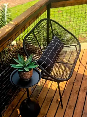 a chair and a table with a pillow on a porch at Tin Town Glamping in Haenertsburg