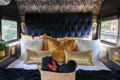 a bedroom with a bed with gold pillows at Tin Town Glamping in Haenertsburg