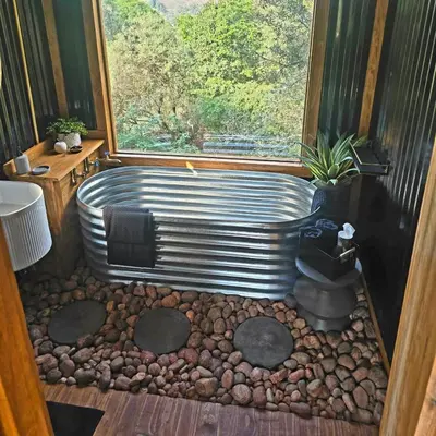 a bath tub in a room with a window at Tin Town Glamping in Haenertsburg