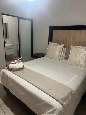 a bedroom with a large white bed with a wooden headboard at TwoHorse Properties in Pretoria