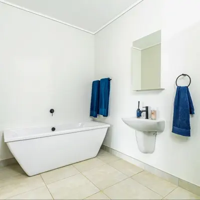 a white bathroom with a tub and a sink at TwoHorse Properties in Pretoria