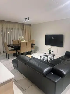 a living room with a black leather couch and a table at TwoHorse Properties in Pretoria