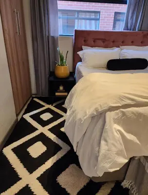 a bedroom with two beds and a black and white rug at Ibunami in Midrand
