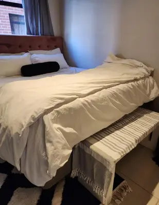 a large white bed with a bench in a bedroom at Ibunami in Midrand
