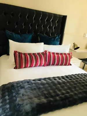 a bed with three pillows and a black headboard at Royal Bliss Lodge and Spa in Midrand