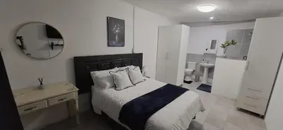 a bedroom with a bed and a table and a mirror at Golden Stay Guest House in Nelspruit