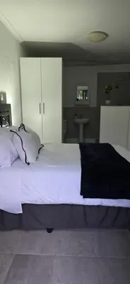 a bedroom with a large bed with white cabinets at Golden Stay Guest House in Nelspruit