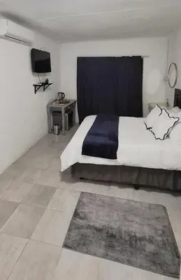 a bedroom with a large bed with a blue curtain at Golden Stay Guest House in Nelspruit