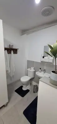 a white bathroom with a toilet and a sink at Golden Stay Guest House in Nelspruit