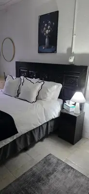 a bedroom with a large bed with a black headboard at Golden Stay Guest House in Nelspruit