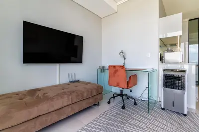 a living room with a couch and a desk and a television at #AlimamaSpaces The Phum's Ellipse in Midrand