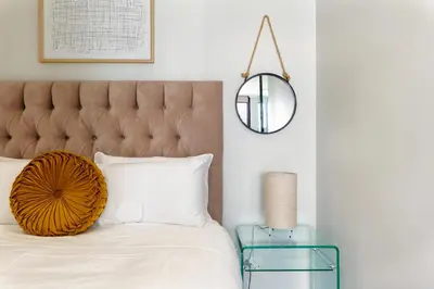 a bedroom with a bed with a mirror and a table at #AlimamaSpaces The Phum's Ellipse in Midrand