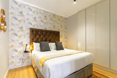 a bedroom with a large bed and a wall at #AlimamaSpaces The Ace's Ellipse in Midrand
