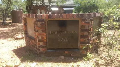 an old brick fireplace in a field with a plaque at Bush Babies Cottage in Marloth Park