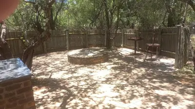a backyard with a fire pit and a wooden fence at Bush Babies Cottage in Marloth Park
